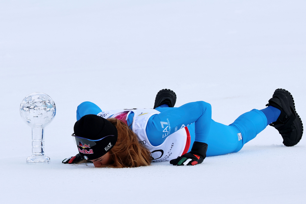 Italy's Sofia Goggia kisses the snow next to the globe trophy for the super-G discipline title after winning an alpine ski, women's super-G race, at the Lillehammer World Cup Finals, in Kvitfjell, Norway, Sunday, March 22, 2026. (AP Photo/Marco Trovati)