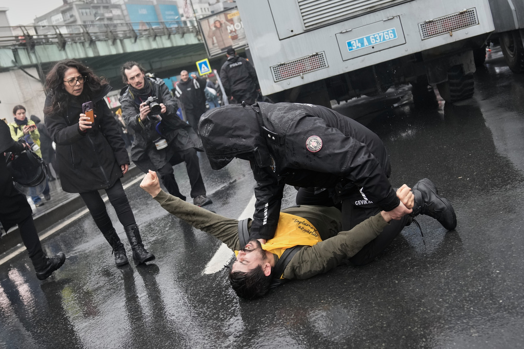 An union member is detained by a Turkish police officer as people try to march towards Taksim square in Istanbul, Turkey, Friday, May 1, 2026, during Labor Day celebrations. (AP Photo/Khalil Hamra)