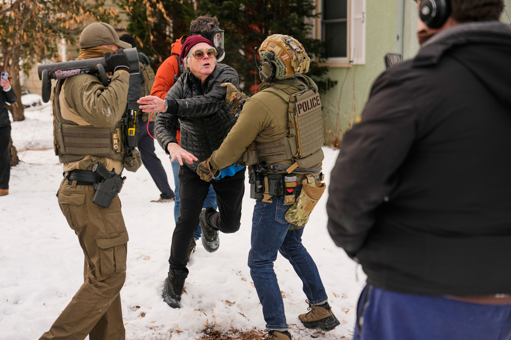 A woman gets into an altercation with a federal immigration officer as officers make an arrest Sunday, Jan. 11, 2026, in Minneapolis. (AP Photo/John Locher)