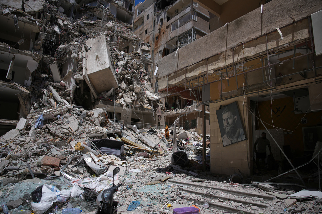 Barber Wissam Srour, 41, right, searches for belongings in the rubble of his barbershop, damaged in an Israeli strike, in the southern port city of Tyre, Lebanon, Friday, June 19, 2026. (AP Photo/Hassan Ammar)