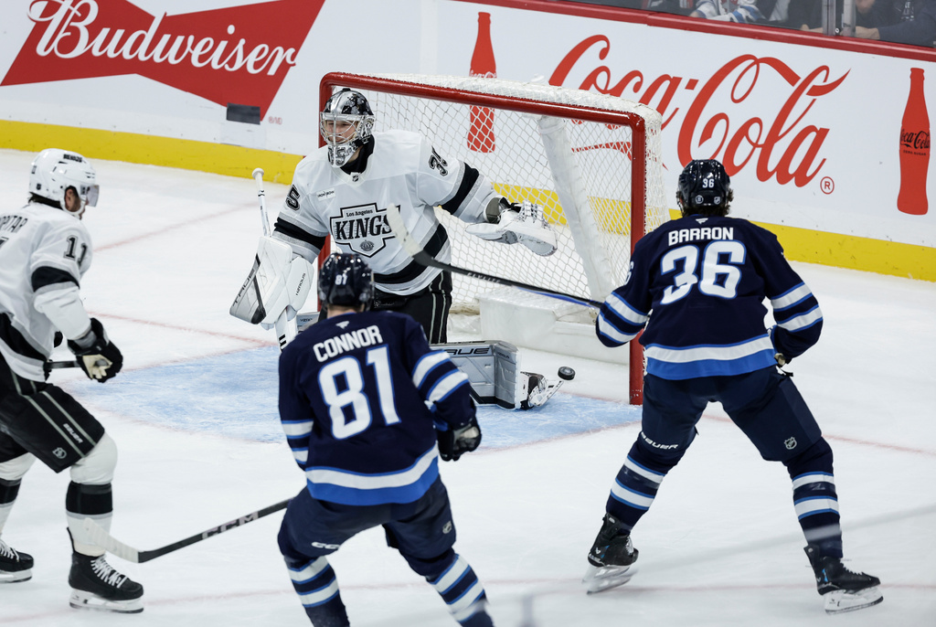 Winnipeg Jets' Kyle Connor (81) and Morgan Barron (36) look on as Mark Scheifele (55) shot gets past Los Angeles Kings goaltender Darcy Kuemper (35) during the second period of an NHL game in Winnipeg, Manitoba, Saturday, Oct. 11, 2025. (John Woods/The Canadian Press via AP)