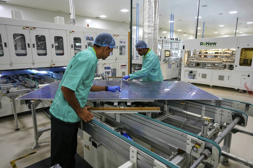 Workers check a solar panel at a ReNew manufacturing plant on the outskirts of Jaipur, India, Thursday, Aug. 21, 2025. (AP Photo/Manish Swarup)