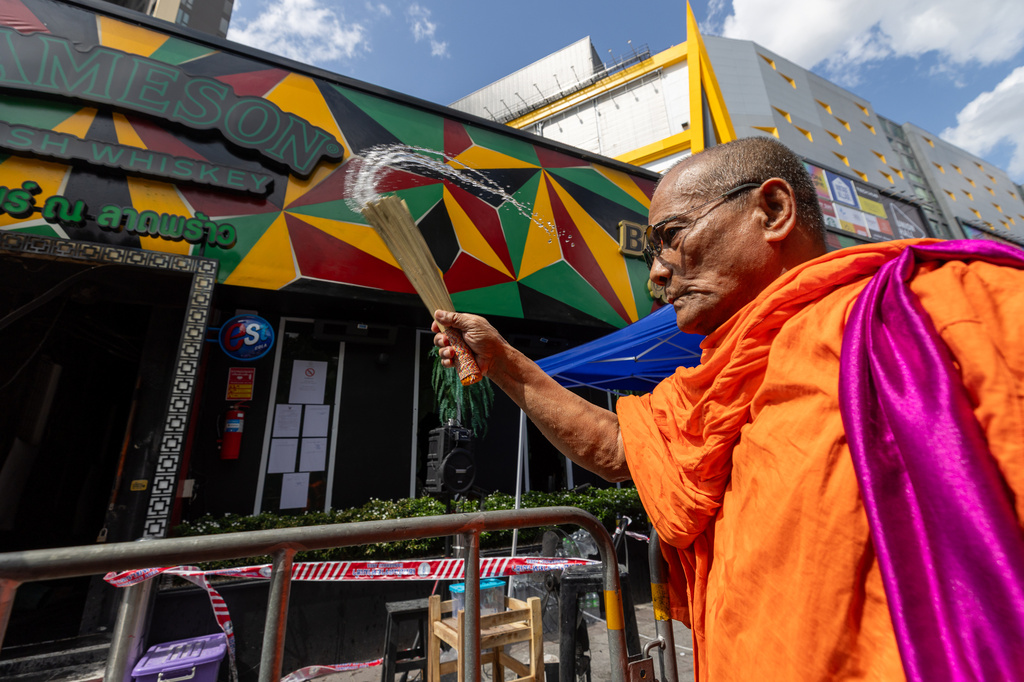 A Buddhist monk sprinkles holy water outside the music bar where a fire killed a number of people in Bangkok, Thailand, Tuesday, July 14, 2026. (AP Photo/Wason Wanichakorn)
