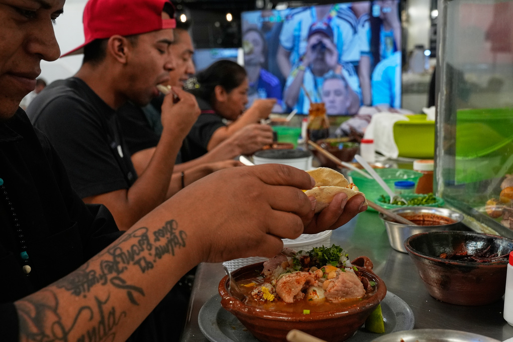 Workers eat at the Juarez market where a monitor shows the World Cup soccer match between Argentina and Austria in Mexico City, Monday, June 22, 2026. (AP Photo/Marco Ugarte)