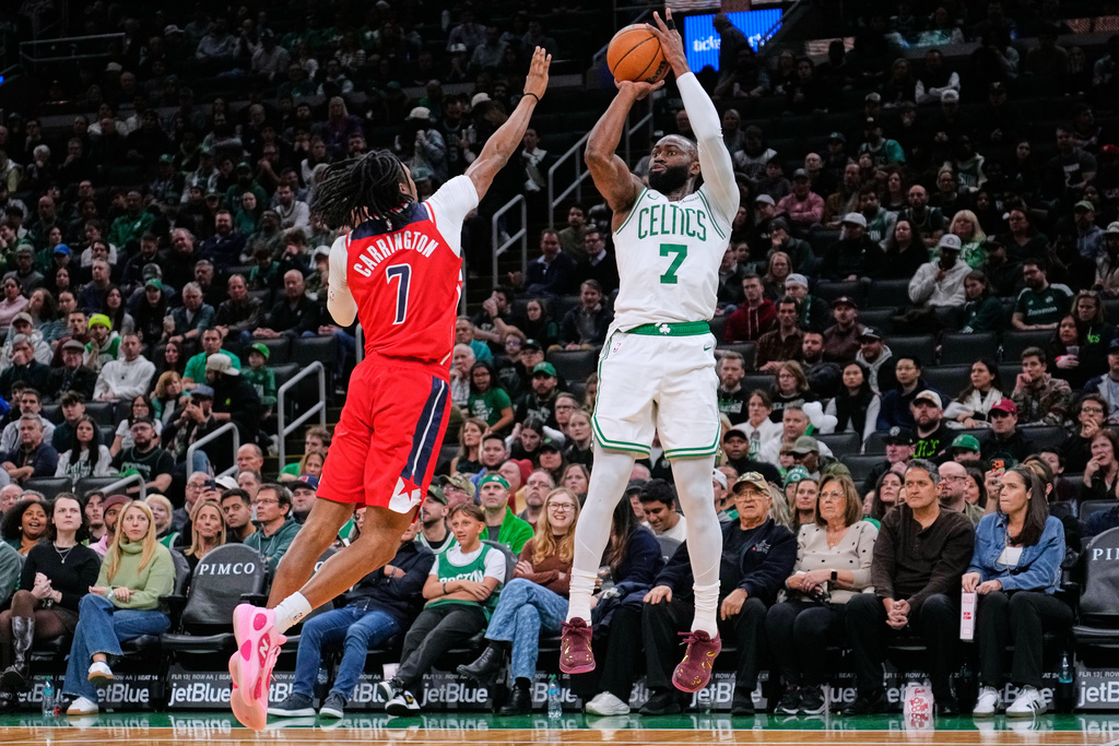 Boston Celtics forward Jaylen Brown, right, shoots a 3-pointer over Washington Wizards guard Bub Carrington during the first half of an NBA basketball game, Wednesday, Nov. 5, 2025, in Boston. (AP Photo/Charles Krupa)