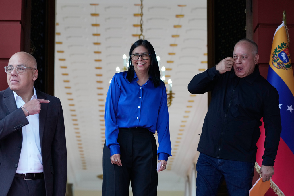 Venezuela's acting President Delcy Rodriguez, center, smiles flanked by Interior Minister Diosdado Cabello, right, and National Assembly President, her brother, Jorge Rodriguez, as they prepare to make a statement at Miraflores presidential palace in Caracas, Venezuela, Wednesday, Jan. 14, 2026. (AP Photo/Ariana Cubillos)