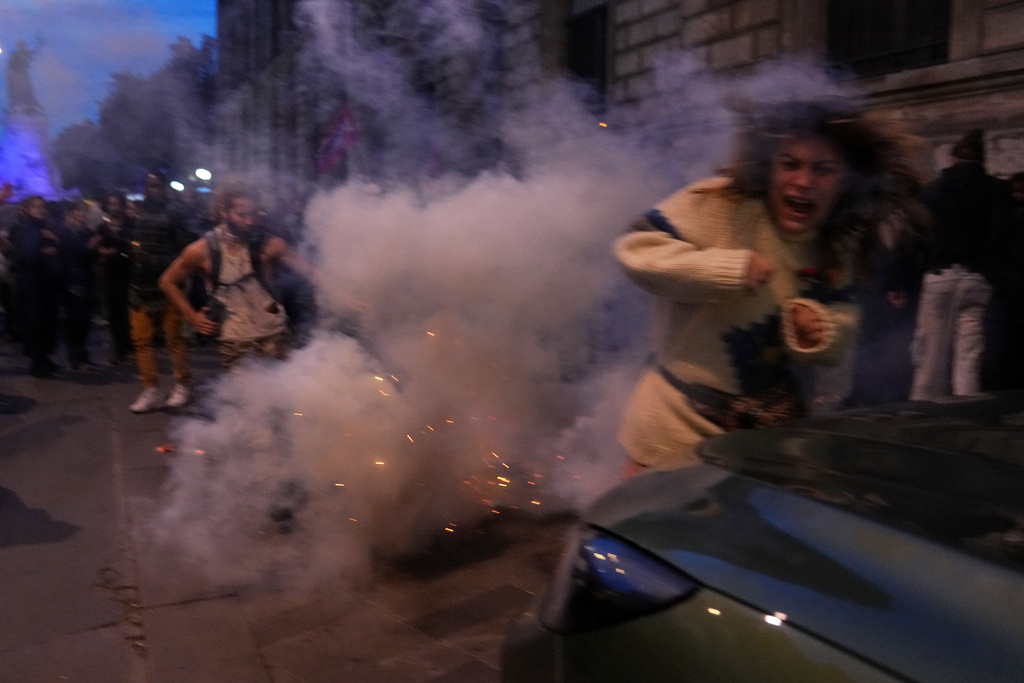 A protester tries to avoid tear gas during a demonstration after a Gaza-bound aid flotilla was intercepted by Israeli Defense Forces in the Mediterranean Sea, Thursday, Oct. 2, 2025 in Paris. (AP Photo/Thibault Camus)