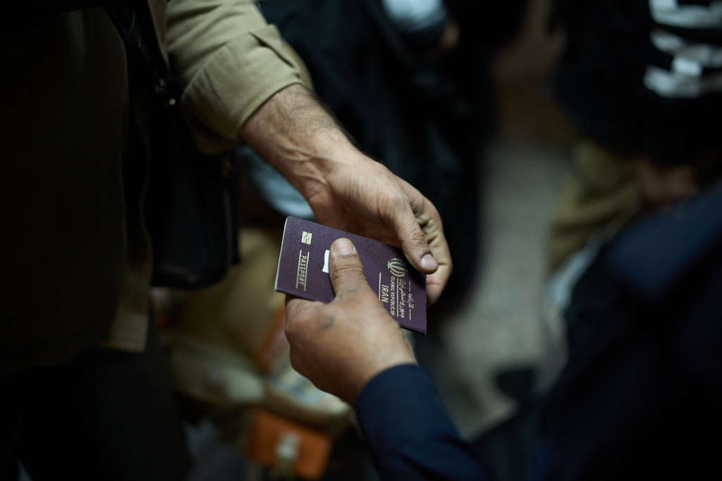 An Iraqi border police officer checks the passport of a man arriving from Iran as he crosses the Shalamcheh border crossing between Iran and Iraq, near Basra, Iraq, Sunday, March 29, 2026. (AP Photo/Leo Correa)