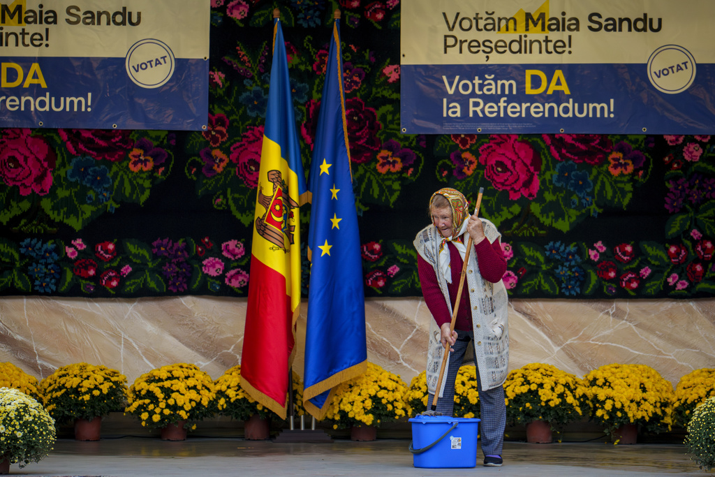 FILE - A woman mops a stage before an electoral rally of Moldova's President Maia Sandu in Magdacesti, Moldova, Oct. 17, 2024. (AP Photo/Vadim Ghirda, File)