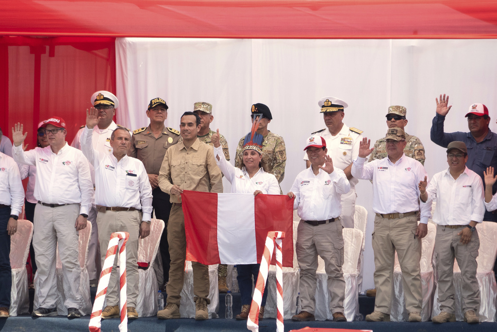 Peru's President Dina Boluarte holds a Peruvian flag during a visit to Santa Rosa, Peru, an island on the Amazon River at the triple border with Colombia and Brazil, amid a territorial dispute with Colombia, Friday, Aug. 15, 2025. (AP Photo/Daniel Padilla)