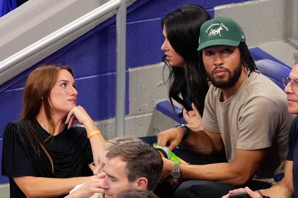 Hannah Berner, left, speaks with Ali Brunson as New York Knicks' Jalen Brunson sits next to her at a match between Ben Shelton, of the United States, and Frances Tiafoe, of the United States, during the men's singles semifinals of the U.S. Open tennis championships Friday, Sept. 11, 2026, in New York. (AP Photo/Yuki Iwamura)