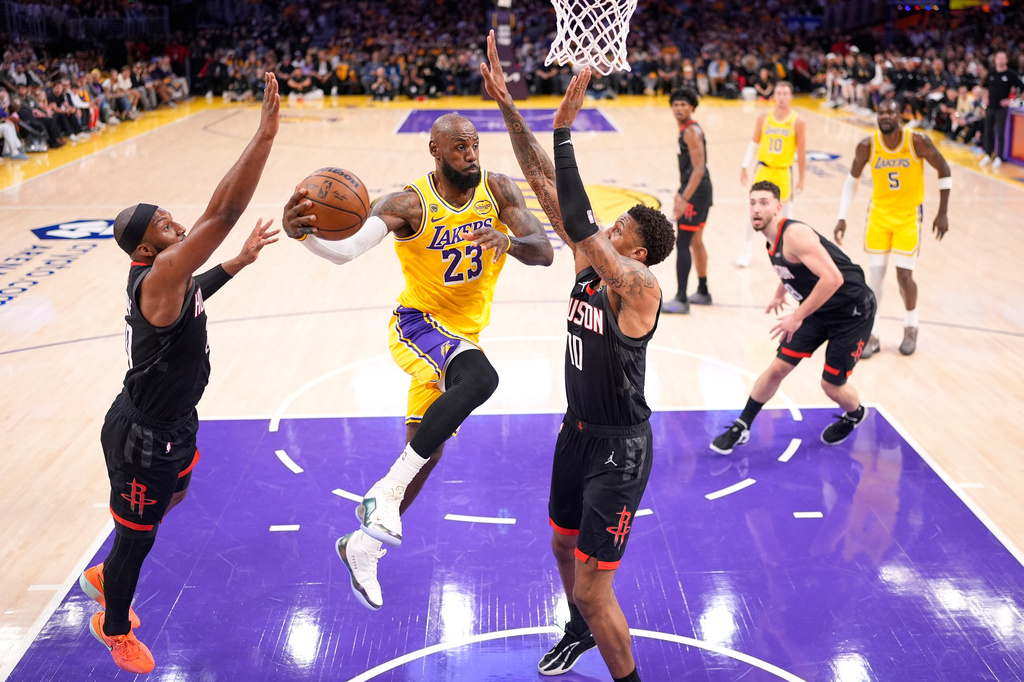 Los Angeles Lakers forward LeBron James, second from left, passes the ball as Houston Rockets guard Josh Okogie, left, and forward Jabari Smith Jr. defend during the first half in Game 1 of a first-round NBA playoffs basketball series Saturday, April 18, 2026, in Los Angeles. (AP Photo/Mark J. Terrill)