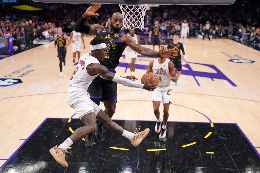 Cleveland Cavaliers guard Dennis Schroder, left, passes the ball as Los Angeles Lakers forward LeBron James defends during the first half of an NBA basketball game Tuesday, March 31, 2026, in Los Angeles. (AP Photo/Mark J. Terrill)