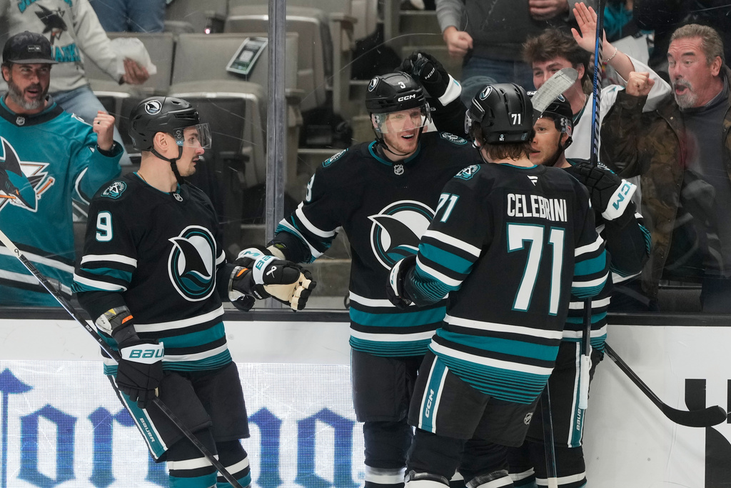 San Jose Sharks defenseman John Klingberg, middle, is congratulated by defenseman Dmitry Orlov (9), center Macklin Celebrini (71) and left wing Jeff Skinner after scoring against the Calgary Flames during the first period of an NHL hockey game in San Jose, Calif., Tuesday, Dec. 16, 2025. (AP Photo/Jeff Chiu)