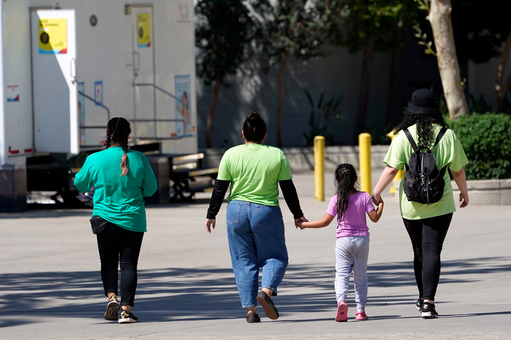FILE - A child holds hands with workers at an emergency shelter for migrant children, July 2, 2021, in Pomona, Calif. (AP Photo/Marcio Jose Sanchez, Pool, File)