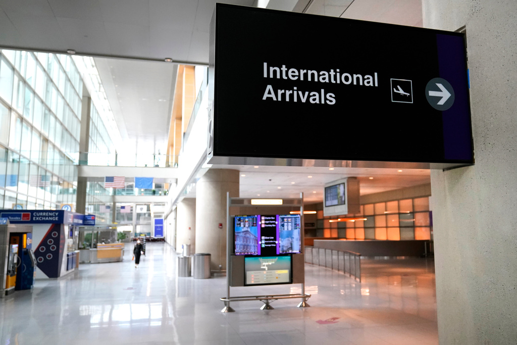 FILE - A sign directs travelers to the international arrival area of a nearly empty Terminal E, where most international flights arrive and depart, at Logan Airport in Boston, Sept. 29, 2020. (AP Photo/Charles Krupa, file)
