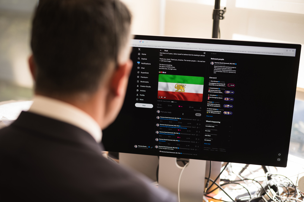 Dr. Houman David Hemmati poses for photos with his social media page displayed on a screen in Santa Monica, Calif., Wednesday, March 11, 2026. (AP Photo/Jae C. Hong)