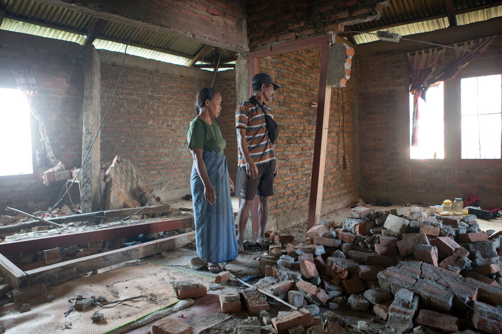 Stefanus Sailon, right, and his wife Sisilia Ilus inspect their house which was damaged during an earthquake in Mbeliling, East Nusa Tenggara province, Indonesia, Sunday, Aug. 16, 2026. (AP Photo/Firdia Lisnawati)