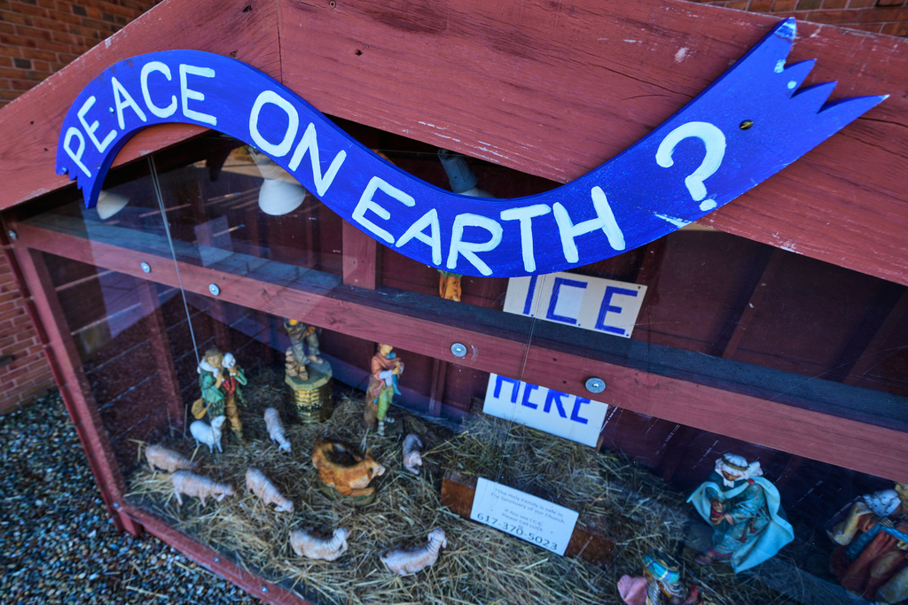 A "PEACE ON EARTH?" sign is posted on the top of a nativity display, which features an ICE WAS HERE sign in the spot for the baby Jesus, outside St. Susanna Church, Tuesday, Dec. 9, 2025, in Dedham, Mass. (AP Photo/Charles Krupa)