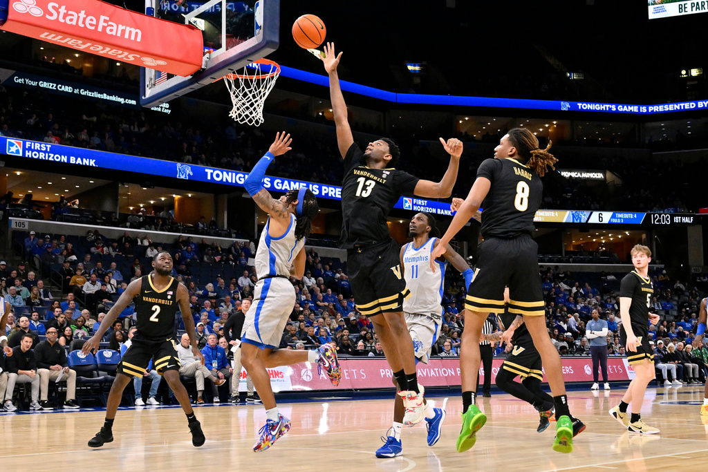 Vanderbilt center Jalen Washington (13) reaches for the ball over Memphis guard Dug McDaniel (1) in the first half of an NCAA college basketball game Wednesday, Dec. 17, 2025, in Memphis, Tenn. (AP Photo/Brandon Dill)