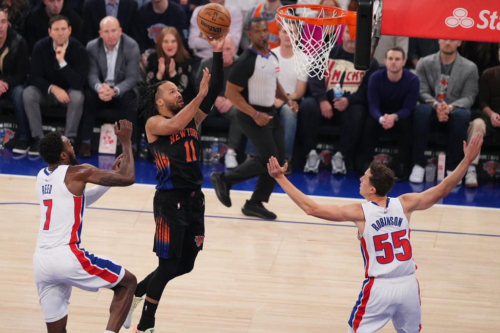 New York Knicks' Jalen Brunson (11) drives past Detroit Pistons' Paul Reed (7) and Duncan Robinson (55) during the first half of an NBA basketball game Tuesday, Oct. 27, 2026, in New York. (AP Photo/Frank Franklin II)
