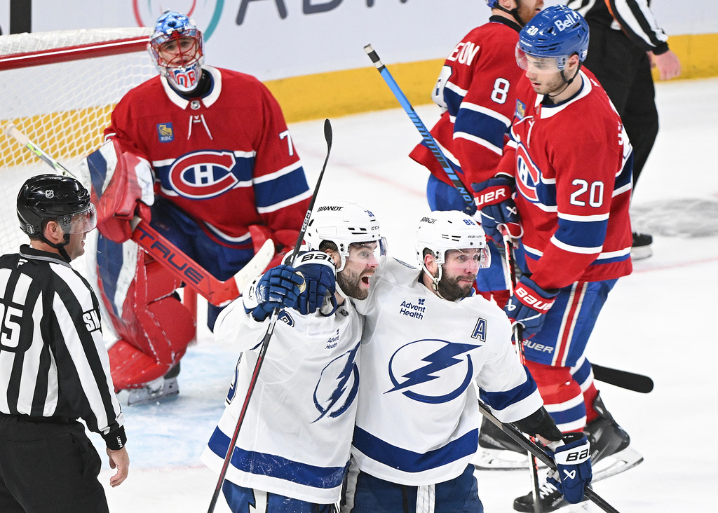 Tampa Bay Lightning's Brandon Hagel (38) celebrates with teammate Nikita Kucherov (86) after scoring against Montreal Canadiens goaltender Jakub Dobes (75) as Canadiens' Juraj Slafkovsky (20) looks on during third period NHL playoff hockey action in Montreal, Sunday, April 26, 2026. (Graham Hughes/The Canadian Press via AP)