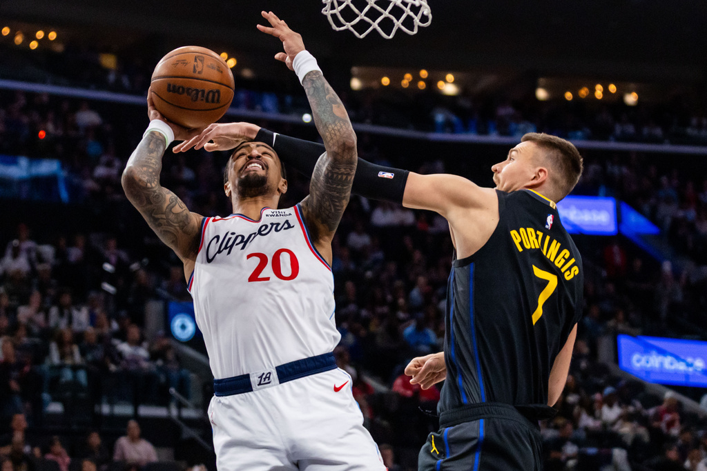 Los Angeles Clippers forward John Collins (20) shoots against Golden State Warriors center Kristaps Porzingis (7) during the first half of an NBA basketball game, Sunday, April 12, 2026, in Inglewood, Calif. (AP Photo/Ethan Swope)