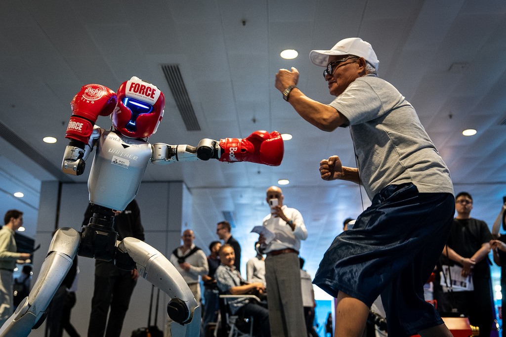 A humanoid robot squares off against a visitor during a demonstration at an exhibition in Hong Kong on Monday, April 13, 2026. (AP Photo/ Chan Long Hei)