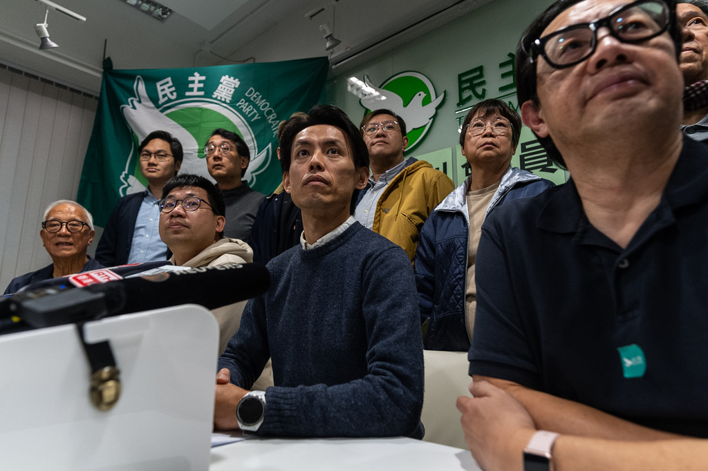 Lo Kin-hei, chairman of Hong Kong's Democratic Party, center, and other committees members pose for photographs at a press conference at the office of Hong Kong's Democratic Party in Hong Kong on Sunday, Dec. 14, 2025. (AP Photo/Chan Long Hei)