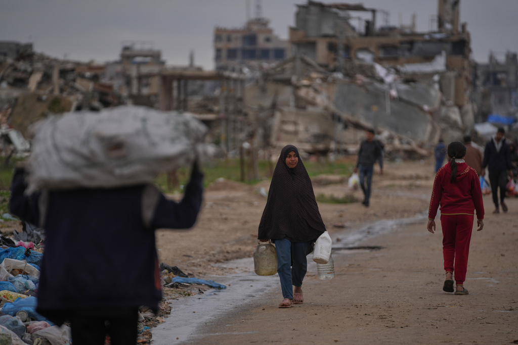 A Palestinian woman carries a container of water in Nuseirat, central Gaza Strip, Friday, Jan. 2, 2026. (AP Photo/Abdel Kareem Hana)