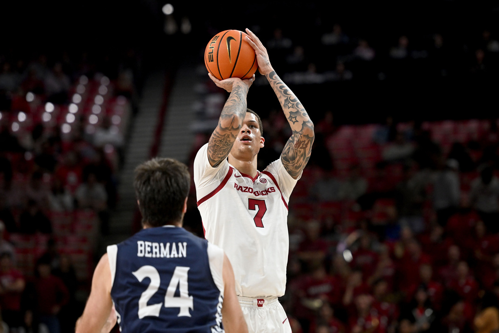 Arkansas forward Trevon Brazile (7) pulls up to his a three point shot over Queens guard Yoav Berman (24) during the first half of an NCAA college basketball game Tuesday, Dec. 16, 2025, in Fayetteville, Ark. (AP Photo/Michael Woods)