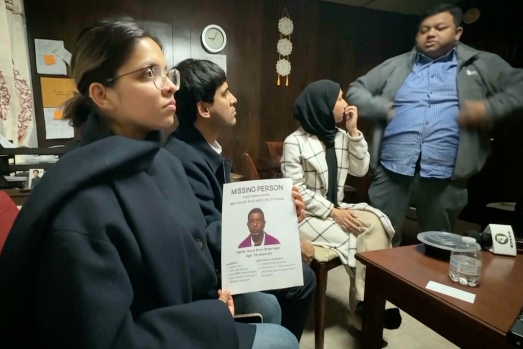 This image made from video provided by WKBW.COM shows a family friend holding a missing person flyer for Nurul Amin Shah Alam, while sitting with other family friends including Khaleda Shah, second from right, and MD Karim, far right, on Wednesday, Feb. 25, 2026, in Buffalo, N.Y. (WKBW.COM via AP)
