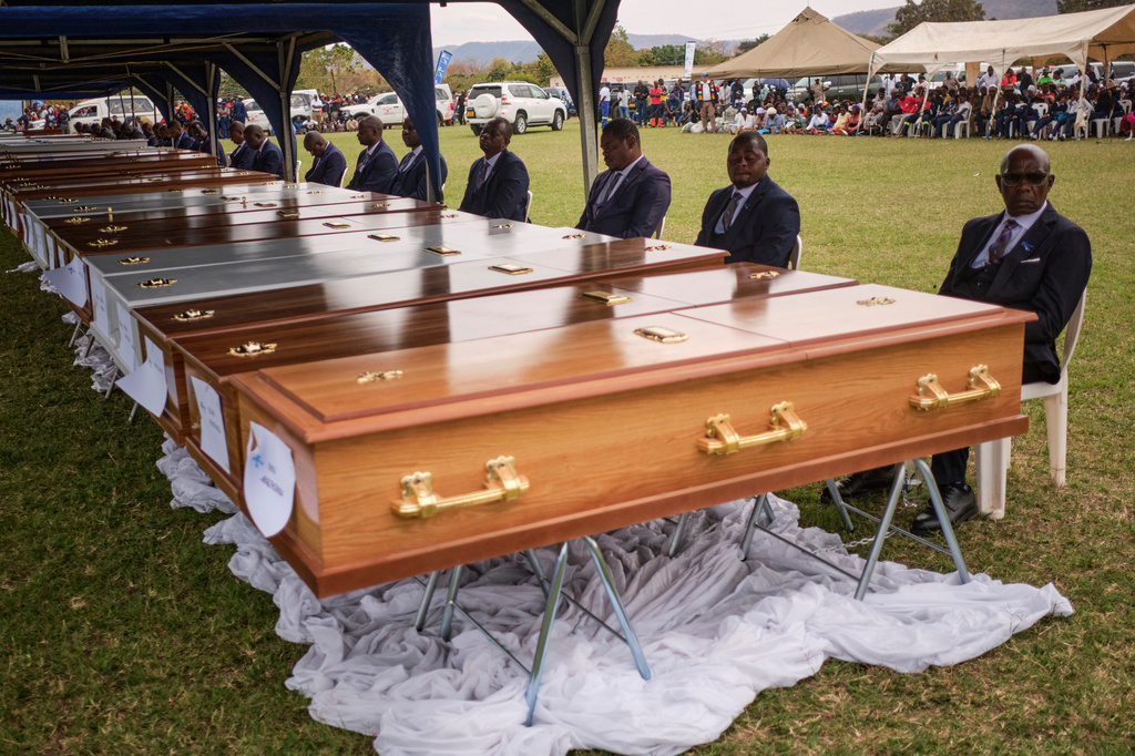 Funeral pallbearers sit behind caskets during a memorial service for the victims of a ferry that capsized on Lake Kariba in Kariba, Zimbabwe, Thursday, Aug. 13, 2026. (AP Photo/Mkhululi Thobela)