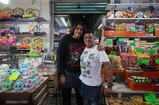 Adrián Chavarría and his son Emmanuel pose for a photo at their stand where they sell sugar skulls known as “calaveritas” or little skulls, traditionally added to Day of the Dead altars honoring deceased loved ones, at the Dulces de Ampudia market in Mexico City, Thursday, Oct. 30, 2025. (AP Photo/Claudia Rosel) Adrián Chavarría and his son Emmanuel pose for a photo at their stand where they sell sugar skulls known as “calaveritas” or little skulls, traditionally added to Day of the Dead altars honoring deceased loved ones, at the Dulces de Ampudia market in Mexico City, Thursday, Oct. 30, 2025. (AP Photo/Claudia Rosel)