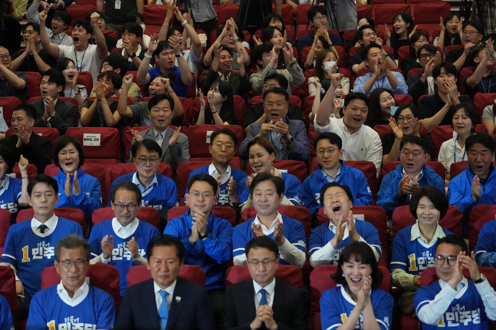 Lawmakers and members of South Korea's ruling Democratic Party react as they watch TV news program about results of exit polls for June 3 nationwide simultaneous local elections at the National Assembly in Seoul, South Korea, Wednesday, June 3, 2026. (AP Photo/Lee Jin-man)