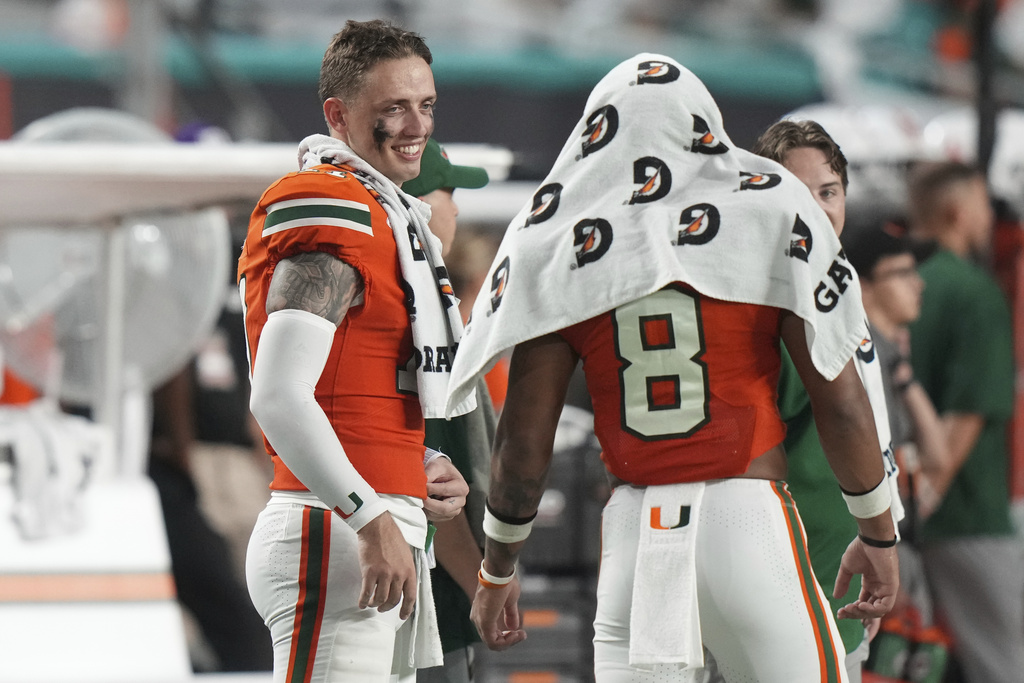 Miami quarterback Carson Beck, left watches from the sideline during the second half of an NCAA college football game against Bethune-Cookman, Saturday, Sept. 6, 2025, in Miami Gardens, Fla. (AP Photo/Lynne Sladky)