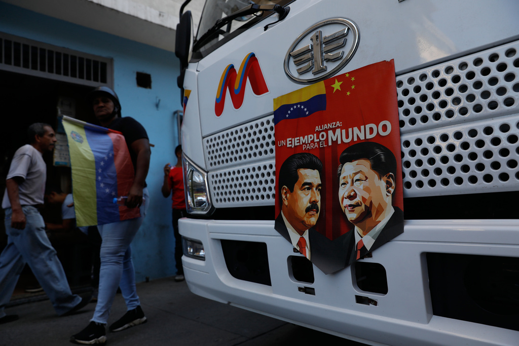 A banner on the front end of a bus features images of Venezuelan President Nicolas Maduro and China's Xi Jinping with a message that reads in Spanish: "An example for the world," during a government-organized rally opposing U.S. intervention, in Caracas, Venezuela, Saturday, Dec. 13, 2025. (AP Photo/Cristian Hernandez)