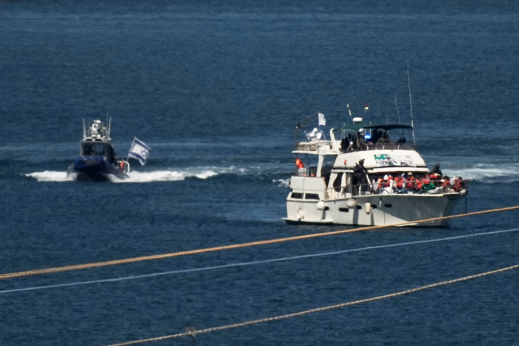 Activists in orange life jackets sit aboard a Gaza-bound Sumud flotilla boat as Israeli navy soldiers sail it into the port of Ashdod, Israel, Thursday, Oct. 2, 2025, after it was intercepted while approaching the Gaza coast. (AP Photo/Leo Correa)
