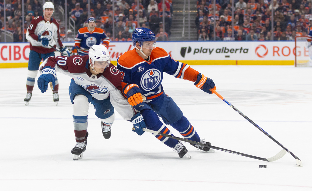 Colorado Avalanche's Sam Malinski (70) and Edmonton Oilers' Jack Roslovic (28) battle for the puck during overtime NHL action, in Edmonton, Alberta, on Monday, April 13, 2026. (Jason Franson/The Canadian Press via AP)