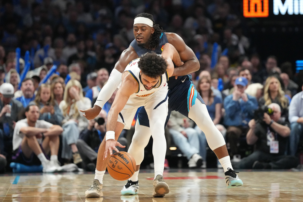 Oklahoma City Thunder guard Luguentz Dort, back, tries to steal the ball from Denver Nuggets guard Jamal Murray during the second half of an NBA basketball game, Friday, Feb. 27, 2026, in Oklahoma City. (AP Photo/Kyle Phillips)