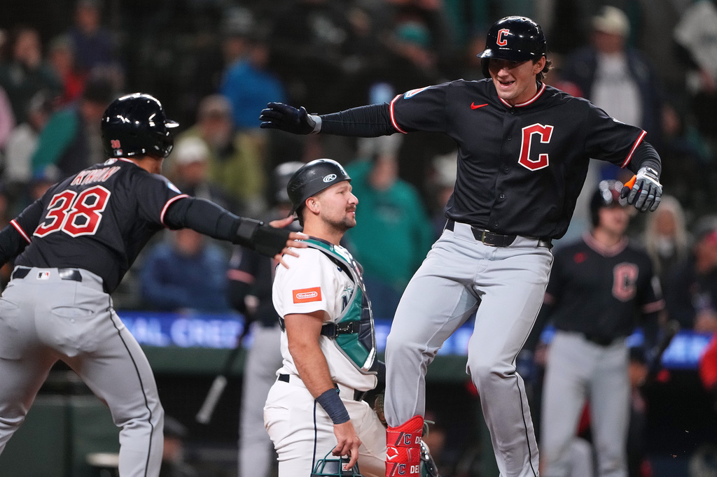 Cleveland Guardians' Chase DeLauter, right, greets Steven Kwan (38) after hitting a two-run home run as Seattle Mariners catcher Cal Raleigh, center, looks away during the 10th inning of a baseball game, Saturday, March 28, 2026, in Seattle. (AP Photo/Lindsey Wasson)