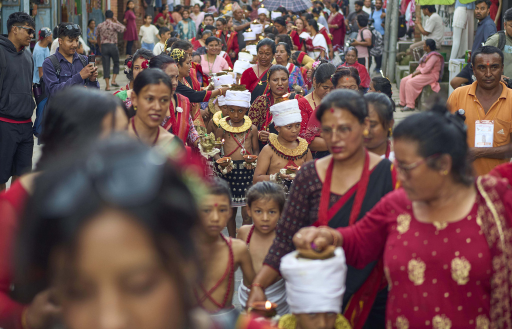 Devotees light oil lamps on their hands, heads, and shoulders during a parade celebrating the birthday of Lord Krishna on Krishna Janmashtami in Bhaktapur,Nepal, Saturday, Aug. 16, 2025. (AP Photo/Niranjan Shrestha)