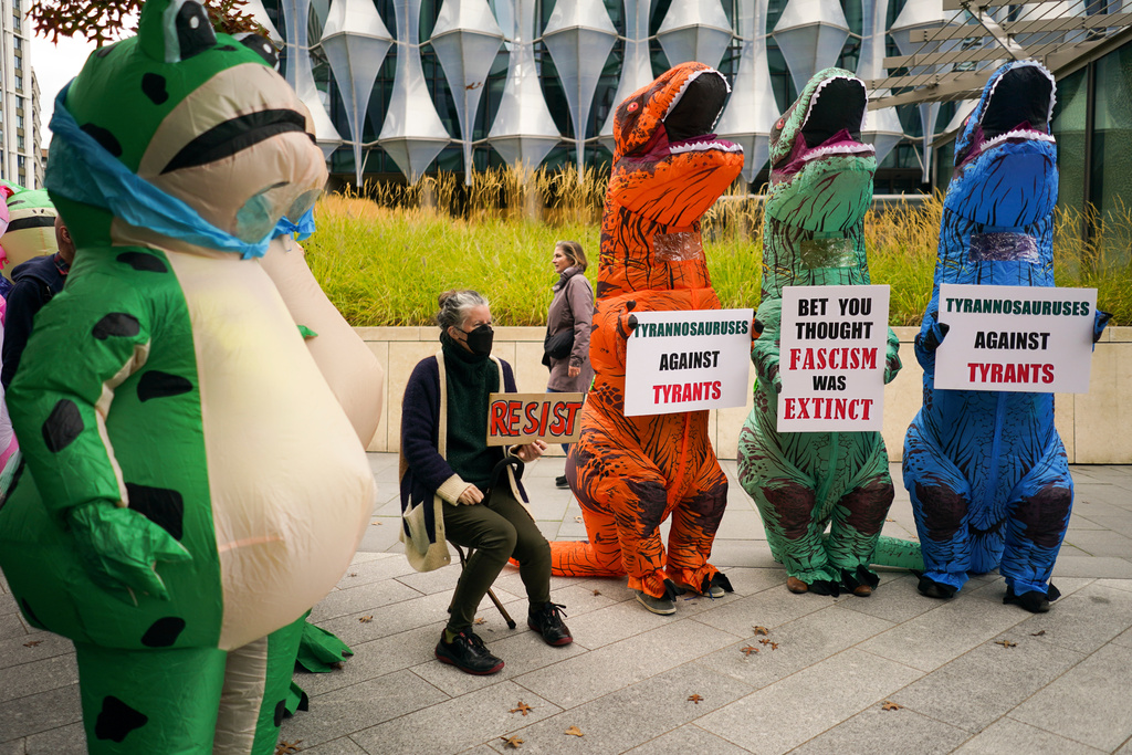 Demonstrators in costumes hold placards during a protest outside the U.S. embassy, in London, Saturday, Oct. 18, 2025.(AP Photo/Alberto Pezzali)