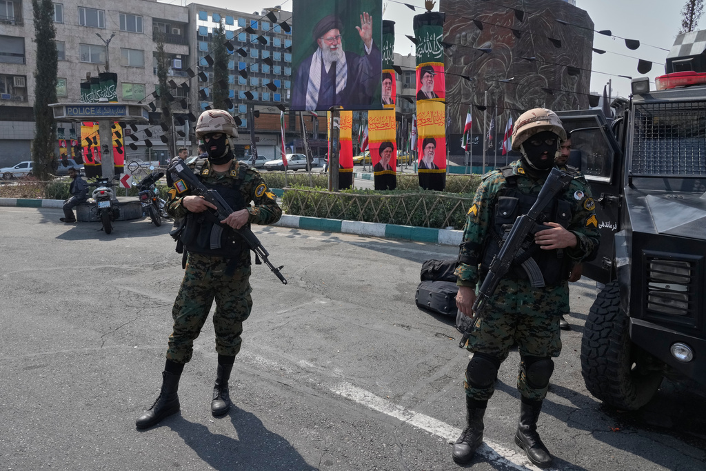 Policemen stand guard next to the banners showing portraits of the late Iranian Supreme Leader Ayatollah Ali Khamenei at the Enqelab-e-Eslami, or Islamic Revolution, square in downtown Tehran, Iran, Saturday, March 14, 2026. (AP Photo/Vahid Salemi)