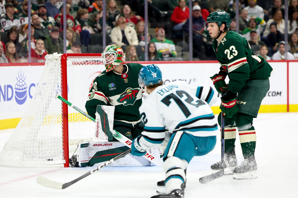 San Jose Sharks left wing William Eklund (72) scores against Minnesota Wild goaltender Jesper Wallstedt, left, while Wild center Marco Rossi (23) looks on during the second period of an NHL hockey game, Sunday, Oct. 26, 2025, in St. Paul, Minn. (AP Photo/Ellen Schmidt)