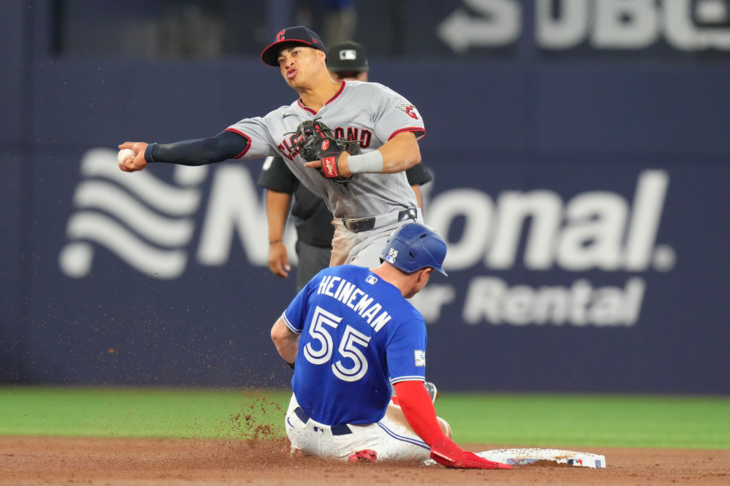 Cleveland Guardians second baseman Juan Brito (34) relays to first for a double play hit into Toronto Blue Jay's Myles Straw after forcing out Blue Jays' Tyler Heineman (55) at second during the third inning of a baseball game in Toronto, Saturday, April 25, 2026. (Chris Young/The Canadian Press via AP)