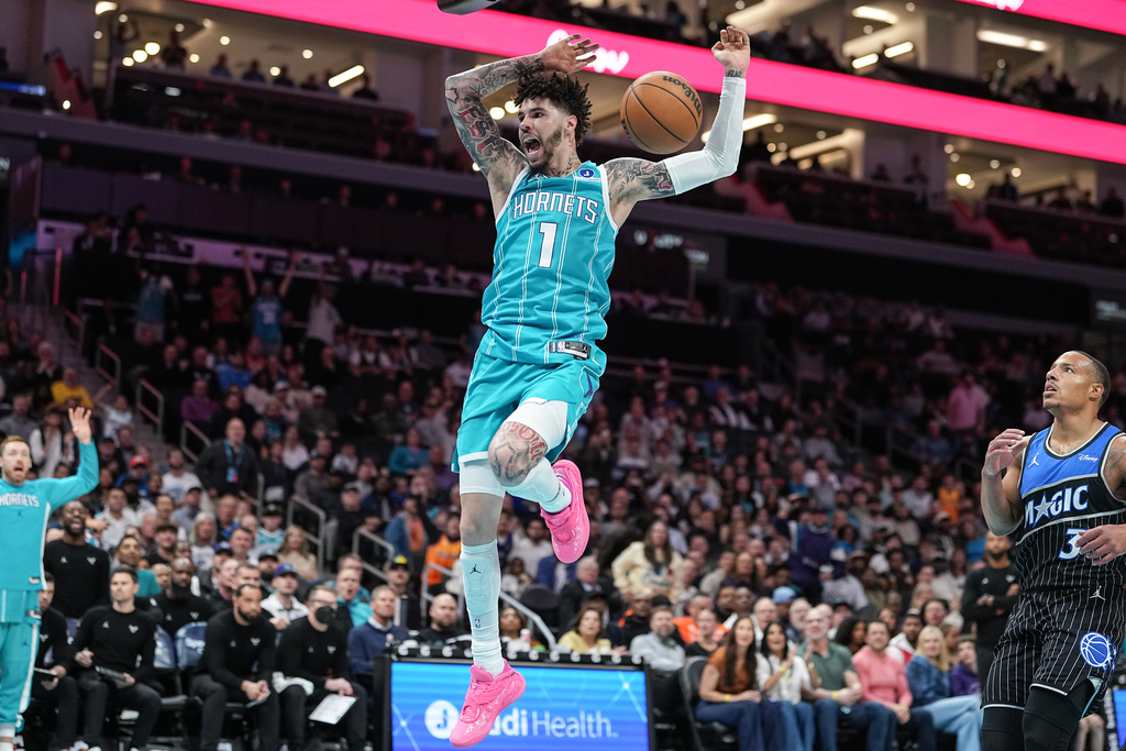 Charlotte Hornets guard LaMelo Ball (1) slam-dunks near Orlando Magic guard Desmond Bane (3) during the first half of an NBA basketball game, Thursday, March 19, 2026, in Charlotte, N.C. (AP Photo/Matt Kelley)