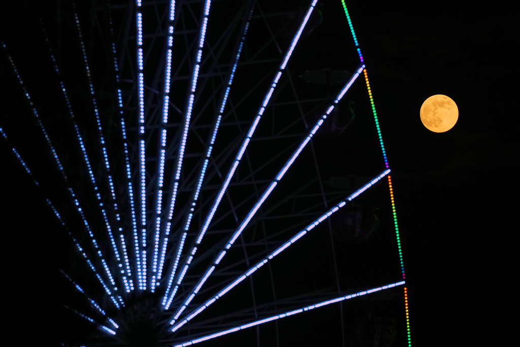 A supermoon, the last full moon of the year, rises up on the sky behind a Christmas celebrations wheel in central capital Nicosia, Cyprus, on Thursday, Dec. 4, 2025. (AP Photo/Petros Karadjias)