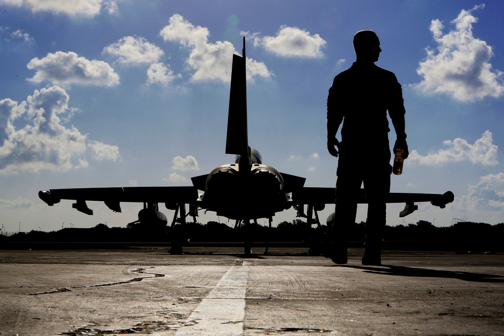 FILE - A British soldier walks by a Typhoon aircraft before take off for a mission in Iraq, at RAF Akrotiri, near the southern coastal city of Limassol, Cyprus, Sept. 22, 2016. (AP Photo/Petros Karadjias, File)