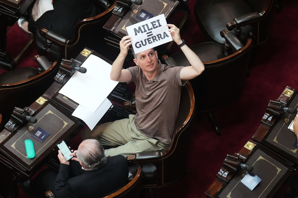 Deputy Juan Marino holds up a placard reading in Spanish, "[Argentina's President Javier] Milei equals war" prior to Milei's delivery of the annual State of the Nation address at Congress in Buenos Aires, Argentina, Sunday, March 1, 2026. (AP Photo/Gustavo Garello)